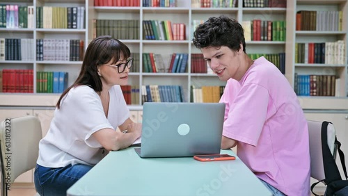 Female college counselor talking with young male student, meeting in library
