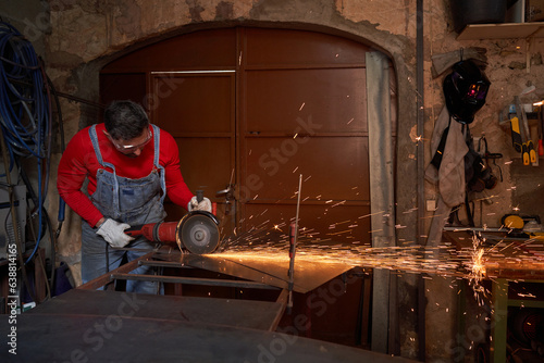 Master cutting metal on workbench with angle grinder