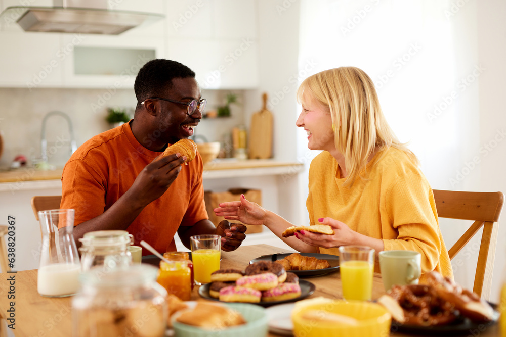 Multiracial couple enjoying breakfast together at home Multiracial couple enjoying breakfast together at home
