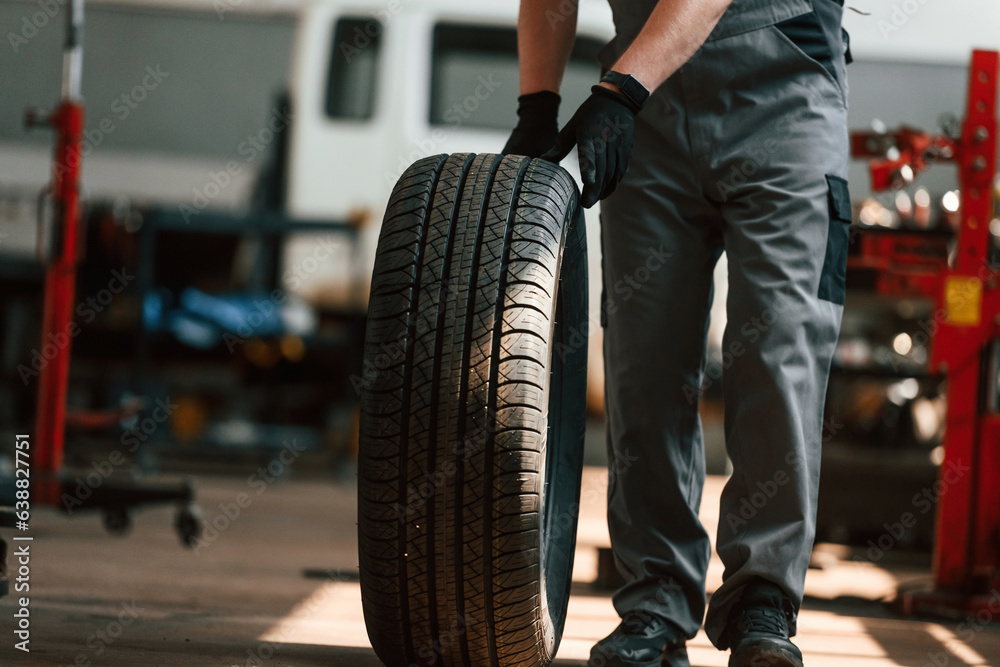 Naklejka premium Close up view of moving the wheel. Man is works in the automobile repairing salon