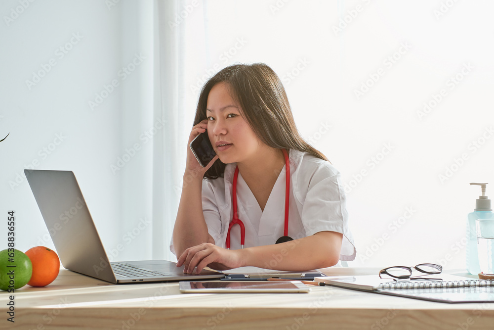 Asian doctor having phone conversation on mobile phone in hospit Asian doctor having phone conversation on mobile phone in hospit