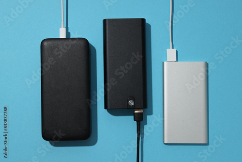 Powerbanks and cords on blue background, top view photo