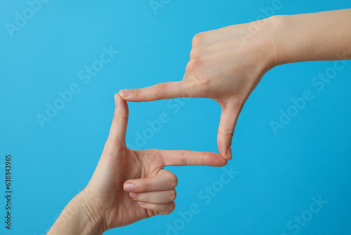 Female hands made a frame from fingers on a blue background