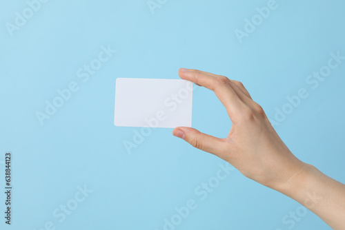 A white blank sheet of paper in the hands of a woman, on a blue background