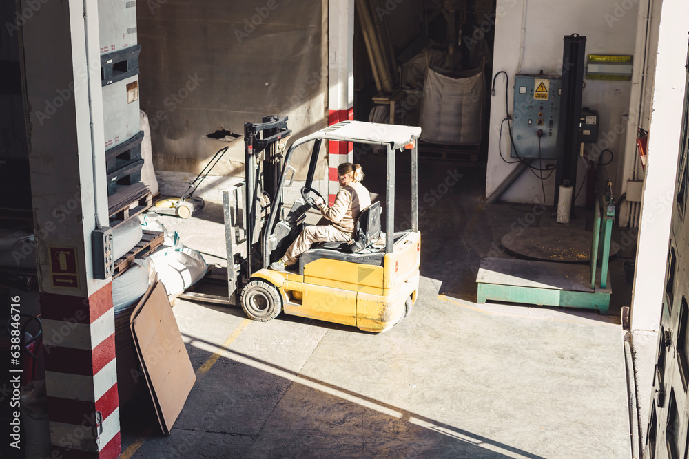 Working woman on a forklift in a warehouse