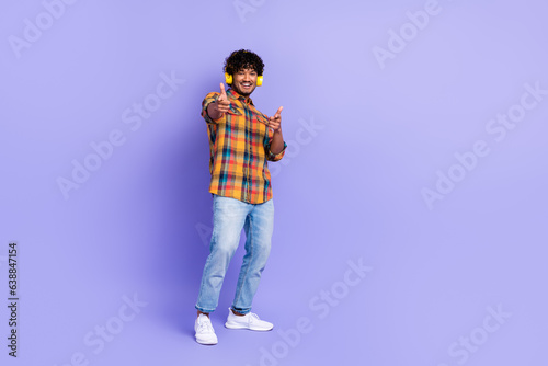 Full body photo of cool clothes hipster guy direct fingers inclusion listen mp3 player earphones party isolated on purple color background