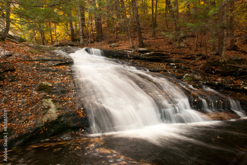 New England waterfalls in autumn. Cascading smooth flowing waterfall with fallen leaves. Waterfall flowing from stream in forest. New England waterfalls in autumn. Cascading smooth flowing waterfall with fallen leaves. Waterfall flowing from stream in forest.