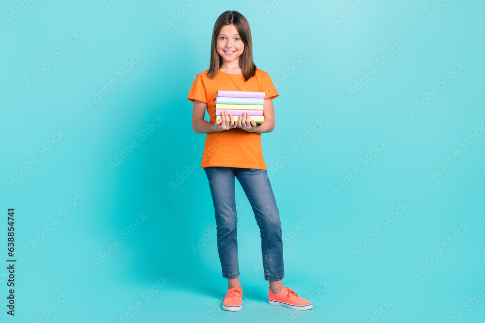 Full length photo of pretty smart clever schoolkid wear stylish orange clothes hold pile stack textbooks isolated on cyan color background Full length photo of pretty smart clever schoolkid wear stylish orange clothes hold pile stack textbooks isolated on cyan color background