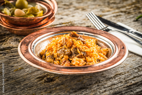 Delicious bulgur pilaf with meat on a bronze plate wooden background