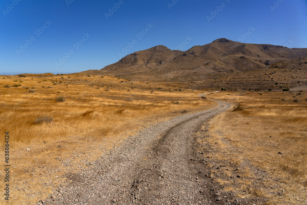 Panoramic view of of mountains with a dirt road in the Gata Cape Natural Park coast. Almería, Andalucía, Spain.