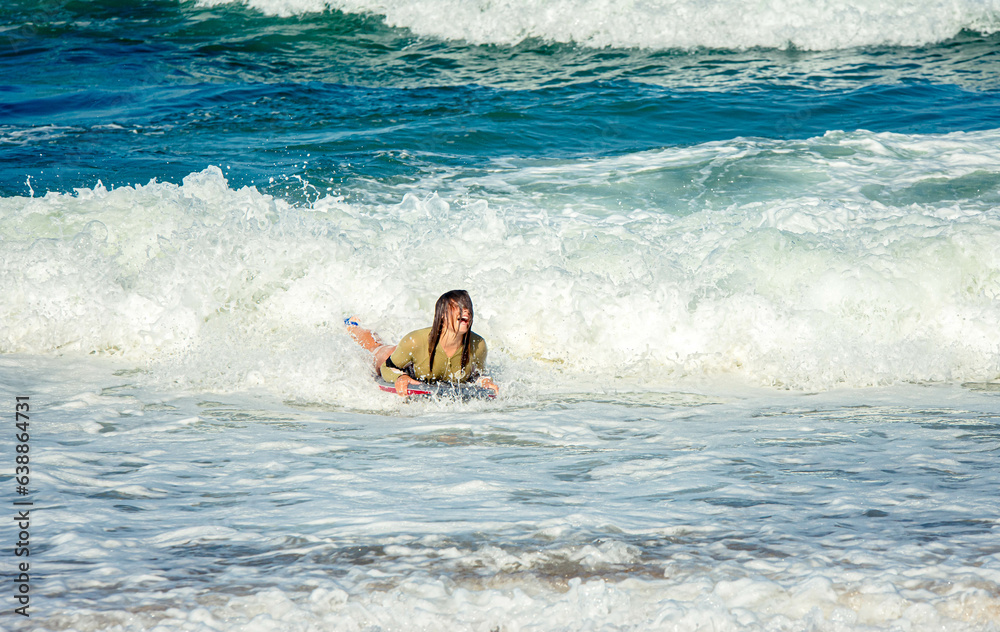Cute young woman with her bodyboard in swimsuit surfing the waves