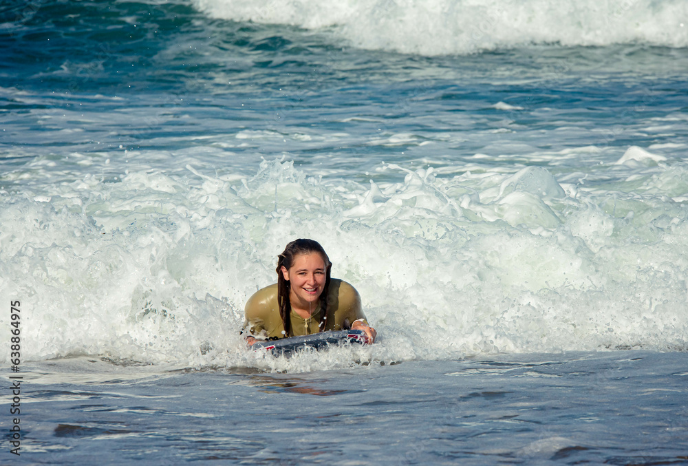 Cute young woman with her bodyboard in swimsuit surfing the waves