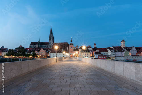 Steinerne Brücke in Regensburg mit Dom und Lichtern in der blauen Stunde.