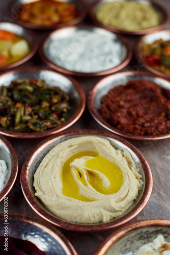 Humus appeteizer in a bronze bowl with other appetizers