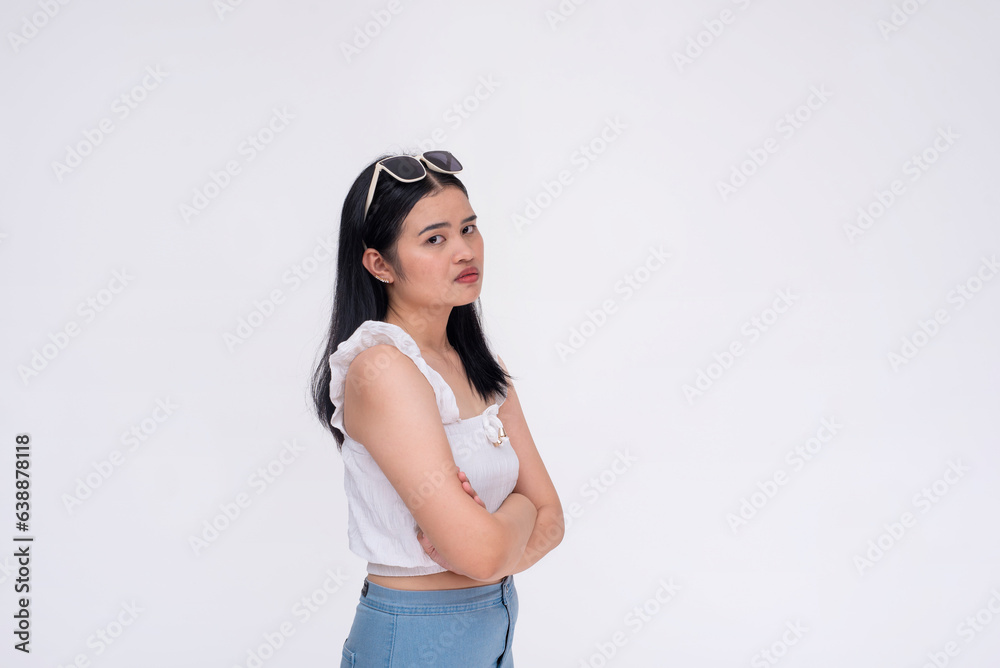A pensive young woman looking upset while crossing her arms. Looking at someone, maybe her boyfriend. isolated on a white backdrop. A pensive young woman looking upset while crossing her arms. Looking at someone, maybe her boyfriend. isolated on a white backdrop.