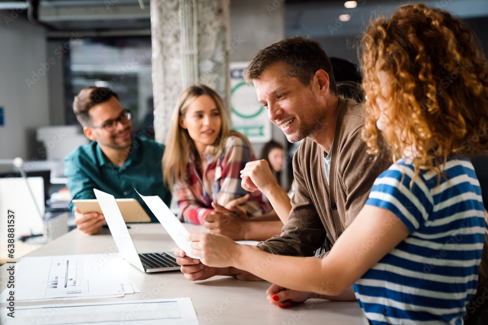 © NDABCREATIVITY - Smiling diverse colleagues gather in boardroom brainstorm discuss financial statistics together