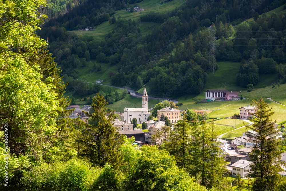 Small town in green summer valley surrounded by mountains in Swiss alps
