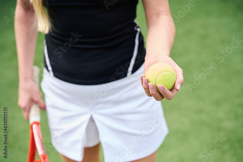 Tennis racket and yellow ball in hands of young woman