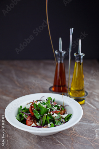 Frest arugula cheese basil salad in a bowl with sauces
isolated black background
