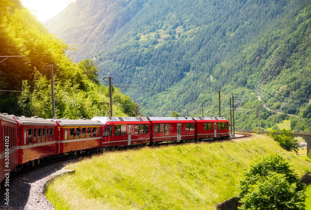 Red train moving in beautiful green summer forest in Switzerland Red train moving in beautiful green summer forest in Switzerland