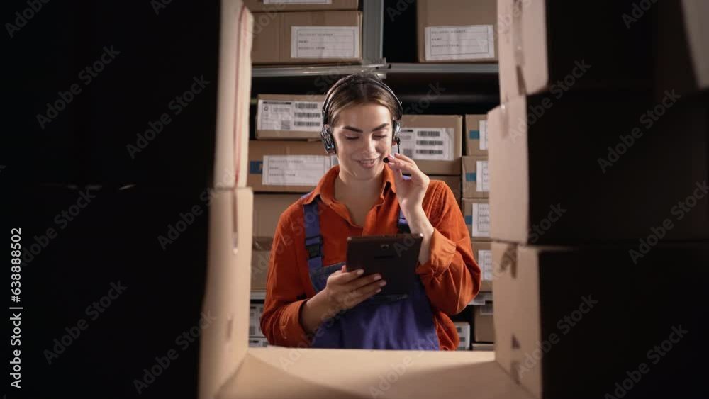 Warehouse woman staff using digital tablet and talking to customer with headset working in distribution center. Call center operator working for online shopping. Warehouse woman staff using digital tablet and talking to customer with headset working in distribution center. Call center operator working for online shopping.