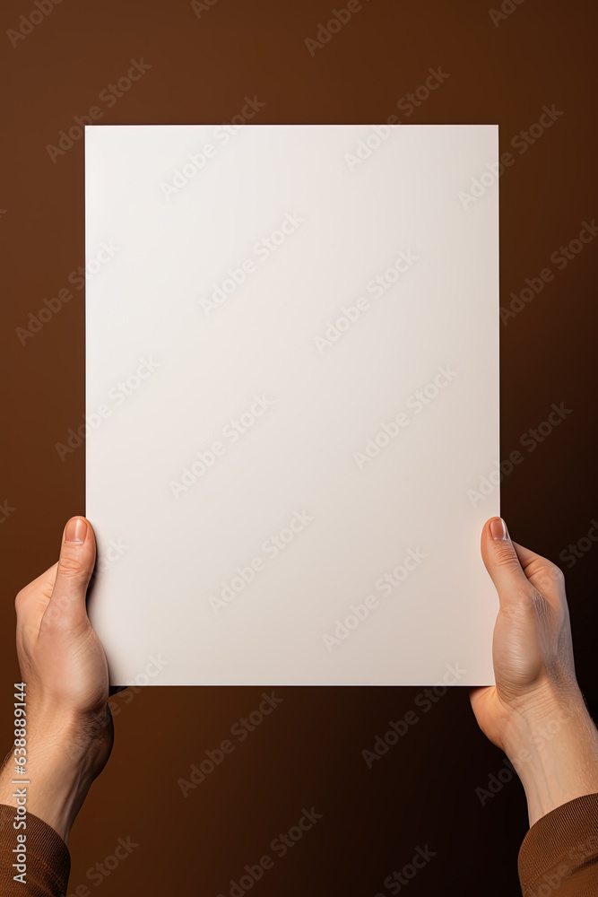 A human hand holding a blank sheet of white paper or card isolated on brown background A human hand holding a blank sheet of white paper or card isolated on brown background