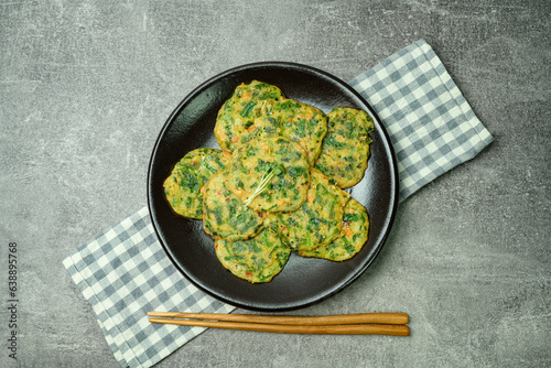buchujeon, korean Chive Pancake, To prepare this dish, chive, julienned carrot, and green pepper are mixed with flour and pan-fried in a flat, round, pancake-like shape.  photo