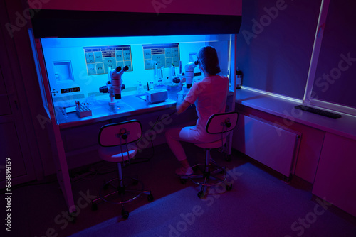 Laboratory assistant works with biomaterial under a powerful microscope photo