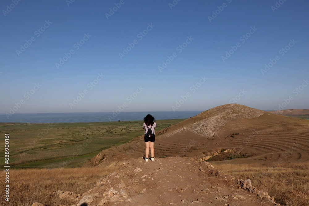 girl watching a beautiful summer landscpae on a hill with a lake