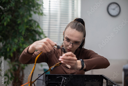 A woman tries to fix a broken computer by taking out cables and other parts.