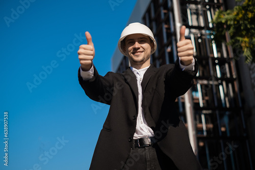 male foreman at construction site showing thumbs up, like, cool job, Architectural engineering holding laptop at construction site, checking plans. Successful engineer or architect