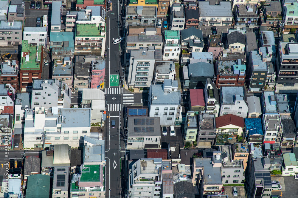 Birds eye view of almost symmetrical  pattern or grid of residential streets and houses in a Tokyo, Japan urban neighborhood (Japanese text on road translates: school zone)