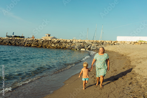 grandmother walks with her grandson on the beach on the sand by the sea
