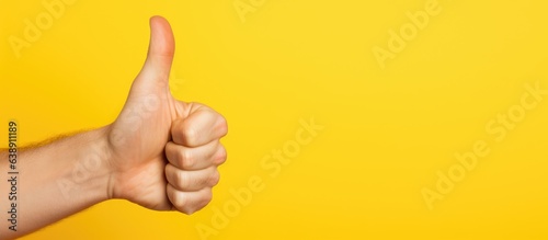 Positive approval thumbs up Hand Gesture on yellow Background photo