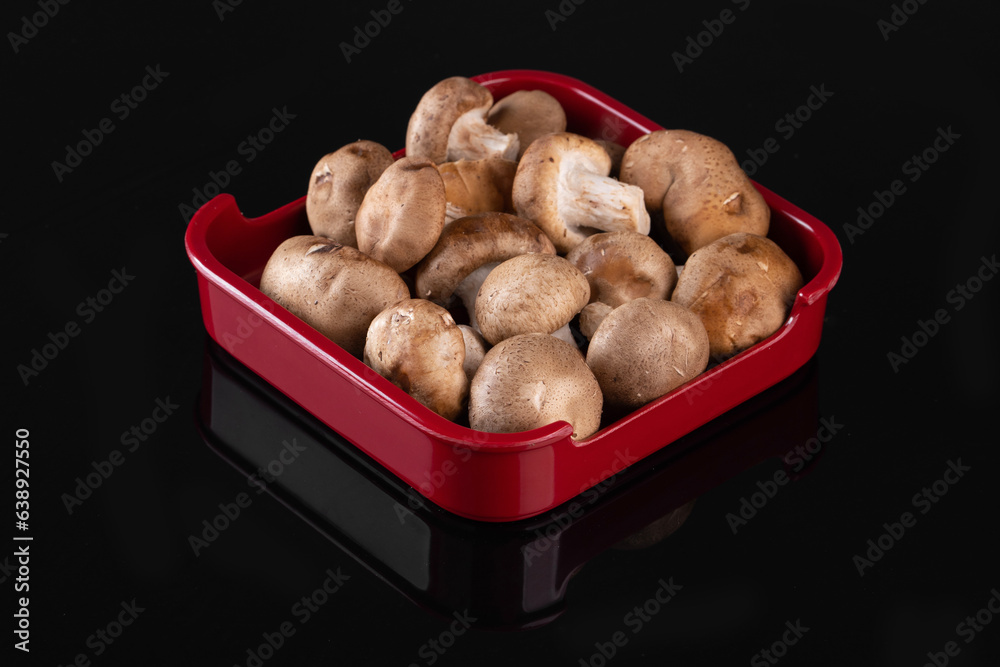 Mushrooms in a red tray are placed on black background. It is cultivated in East Asia and Southeast Asia. Mushrooms in a red tray are placed on black background. It is cultivated in East Asia and Southeast Asia.