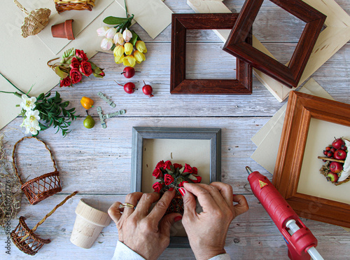 Woman crafting making handmade framed baskets with tiny fruits and flowers arrangements to be sold or for gifts. 