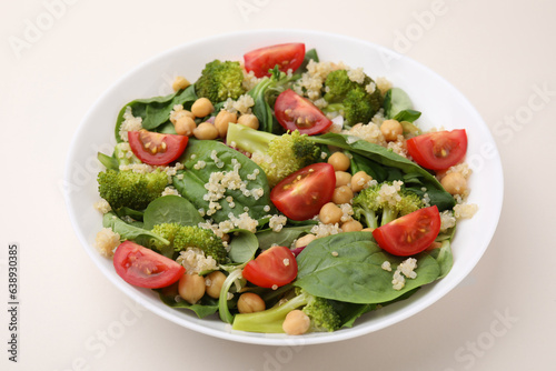 Healthy meal. Tasty salad with quinoa, chickpeas and vegetables on beige table, closeup