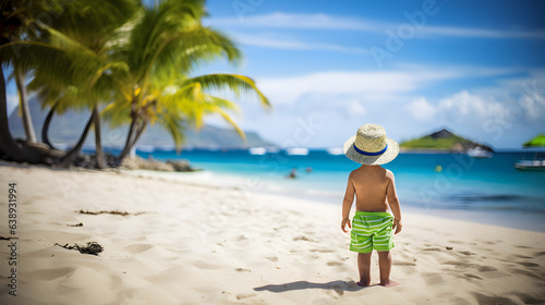 A little boy on vacation on a beach background, back view, looking at the turquoise ocean