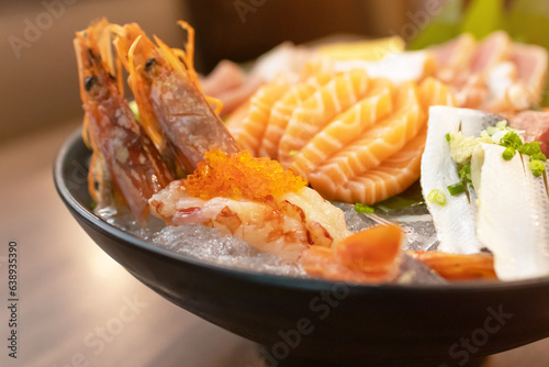 Japanese sashimi set serve on ice with warm light at japanese restaurant.