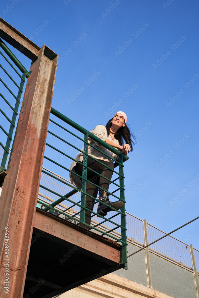 Smiling ethnic woman in pink scarf on grunge balcony