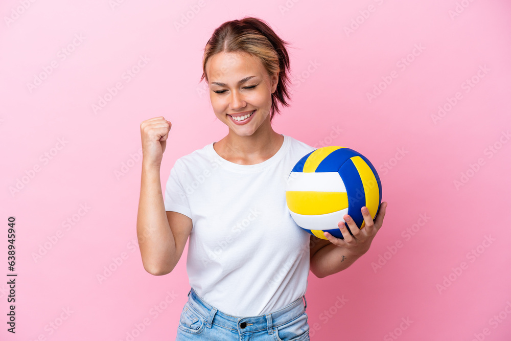 Young Russian woman playing volleyball isolated on pink background celebrating a victory