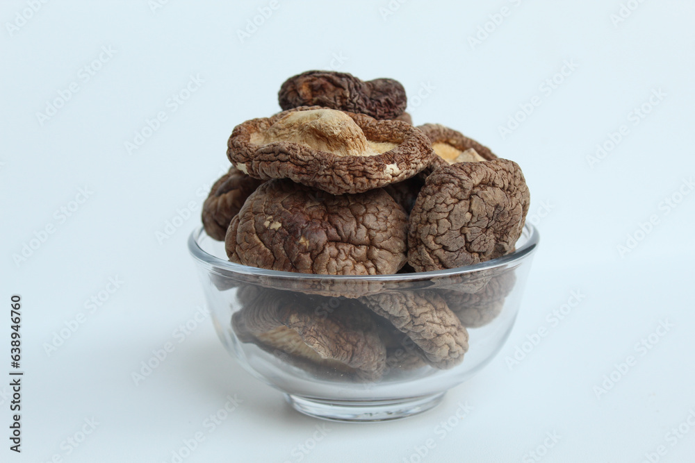 Dried paddy straw mushroom, or straw mushroom, or Volvariella volvacea, on transparent bowl. Isolated on white background Dried paddy straw mushroom, or straw mushroom, or Volvariella volvacea, on transparent bowl. Isolated on white background