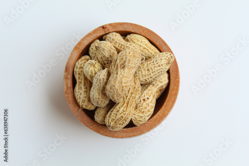 Baked groundnut, Goober or Monkey Nut, or Arachis hypogaea, in a wooden bowl. Isolated on white background. Flat lay or top view photo