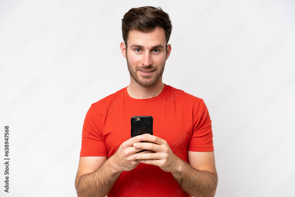 Young caucasian man isolated on white background looking at the camera and smiling while using the mobile Young caucasian man isolated on white background looking at the camera and smiling while using the mobile