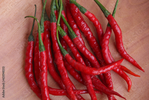 Fresh curly red chilies or cabe merah keriting, on a wooden plate. Main ingredient to make sambal in Indonesia. Flat lay or top view