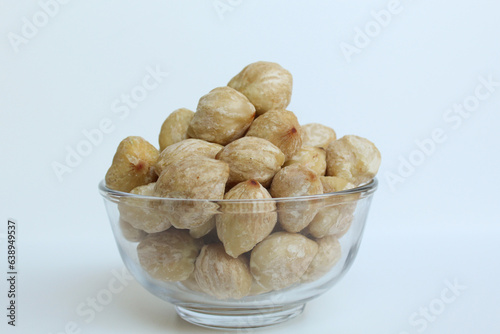 Dried Indonesian Candlenuts, or Kemiri, the seed of Aleurites moluccanus inside a transparant bowl, isolated in white background