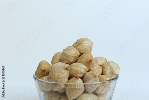 Dried Indonesian Candlenuts, or Kemiri, the seed of Aleurites moluccanus inside a transparant bowl, isolated in white background
