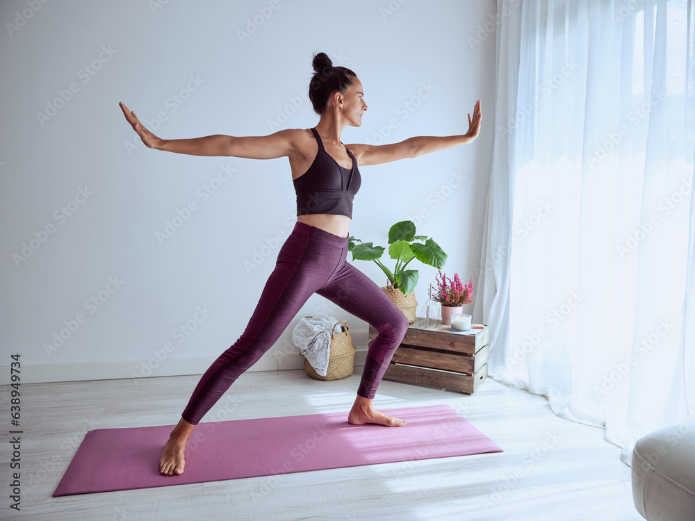 Woman practicing yoga in Warrior pose at home