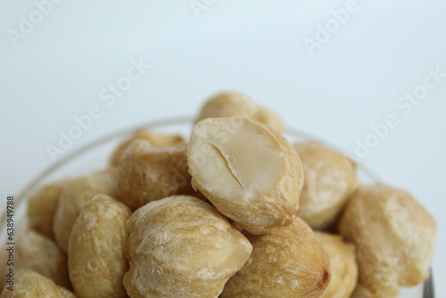 Dried Indonesian Candlenuts, or Kemiri, the seed of Aleurites moluccanus inside a transparant bowl, isolated in white background