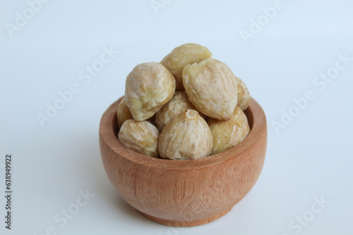 Dried Indonesian Candlenuts, or Kemiri, the seed of Aleurites moluccanus inside a wooden bowl, isolated in white background